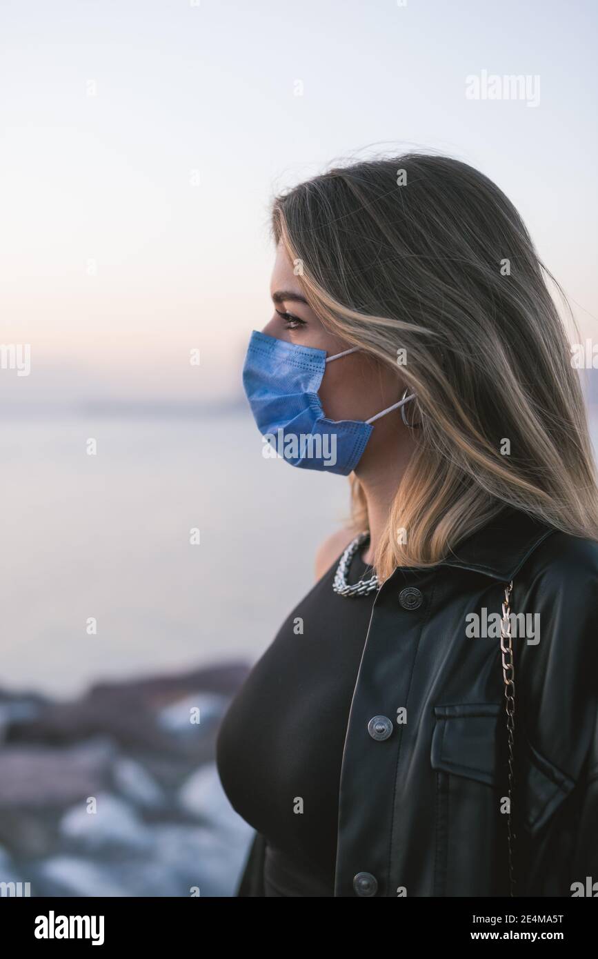 Retrato de una adolescente con una máscara médica en la calle. Foto de stock