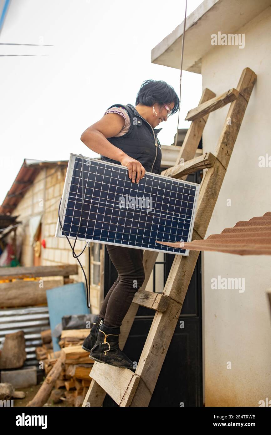 Un técnico de la compañía local de energía sin fines de lucro instala un nuevo sistema de iluminación solar en una casa en Cantel, Guatemala. Foto de stock