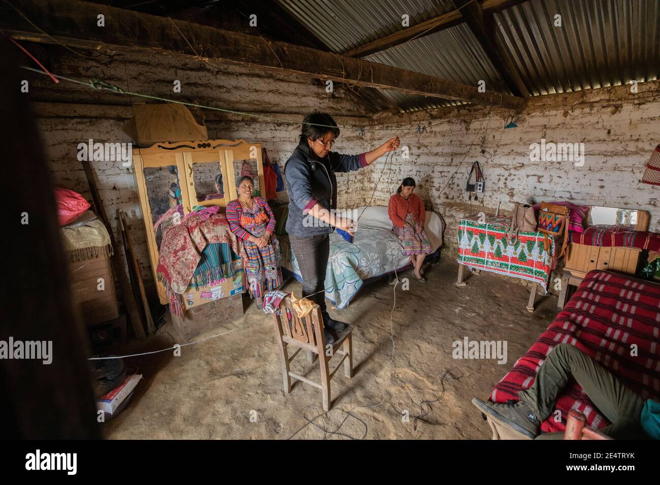 Un técnico de la compañía local de energía sin fines de lucro instala un nuevo sistema de iluminación solar en una casa en Cantel, Guatemala. Foto de stock