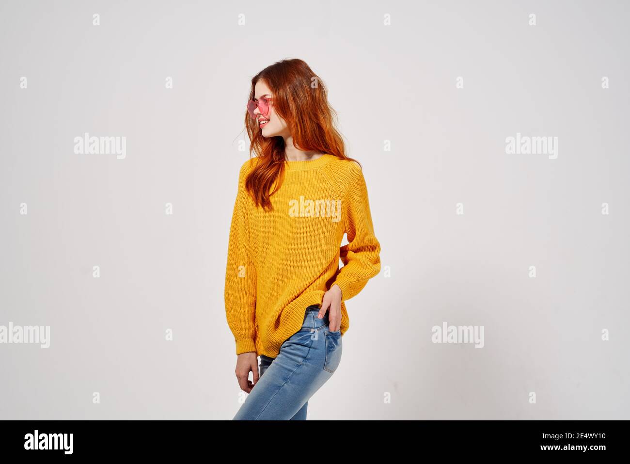 mujer joven y bonita con suéter amarillo y gafas de vaqueros de color rosa  posando Fotografía de stock - Alamy
