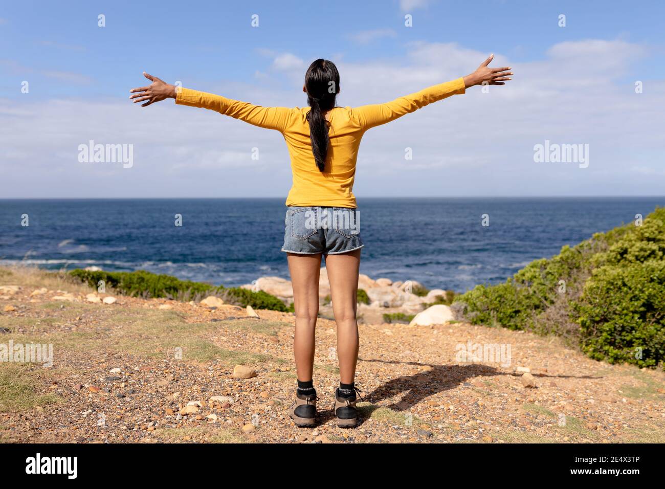 Mujer afroamericana de pie que se extiende brazos en el campo de montaña Foto de stock