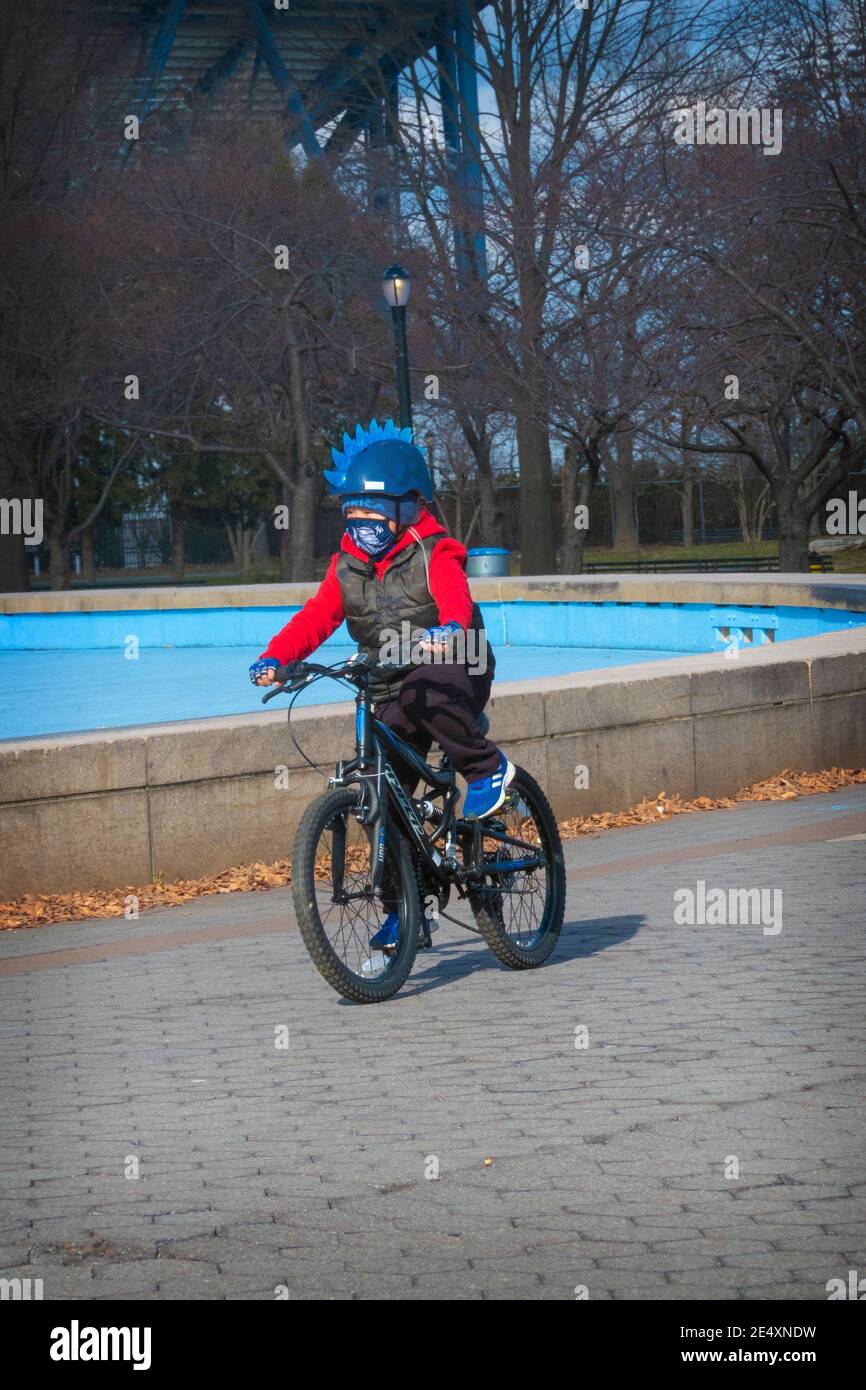 Un joven muchacho con un vistoso casco de mohawk pedalea alrededor de  Unisphere en Flushing Meadows Corona Park en Queens, Nueva York Fotografía  de stock - Alamy