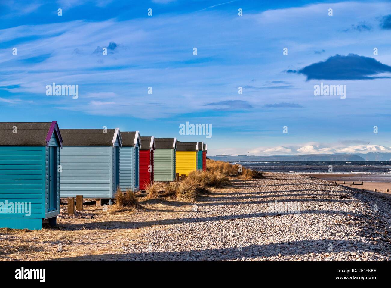 FINDHORN MORAY COSTA ESCOCIA LA PLAYA Y LOS CHALETS DE COLORES O. CABAÑAS EN INVIERNO MONTAÑAS CUBIERTAS DE NIEVE MÁS ALLÁ Foto de stock