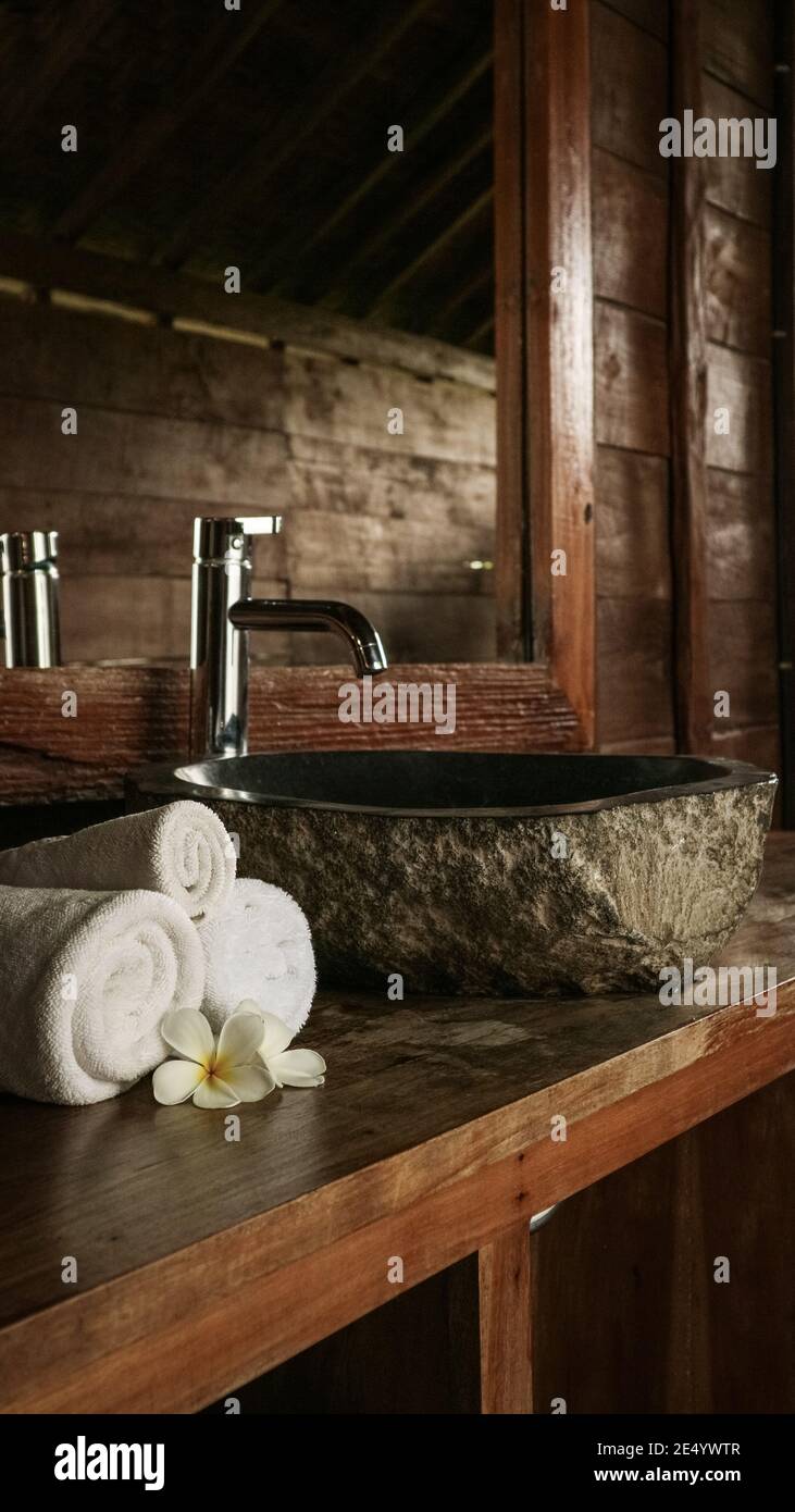 Baño con lavabo de piedra, espejo y toallas en estilo tradicional balinés  en la casa, Indonesia Fotografía de stock - Alamy