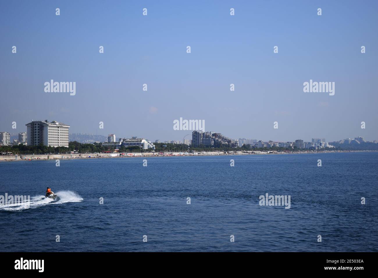 Hombre joven en chaleco salvavidas montando una moto de agua en la alta mar  azul, formando grandes olas, salpicaduras y espuma en el fondo cielo claro.  Mediterranea Fotografía de stock - Alamy