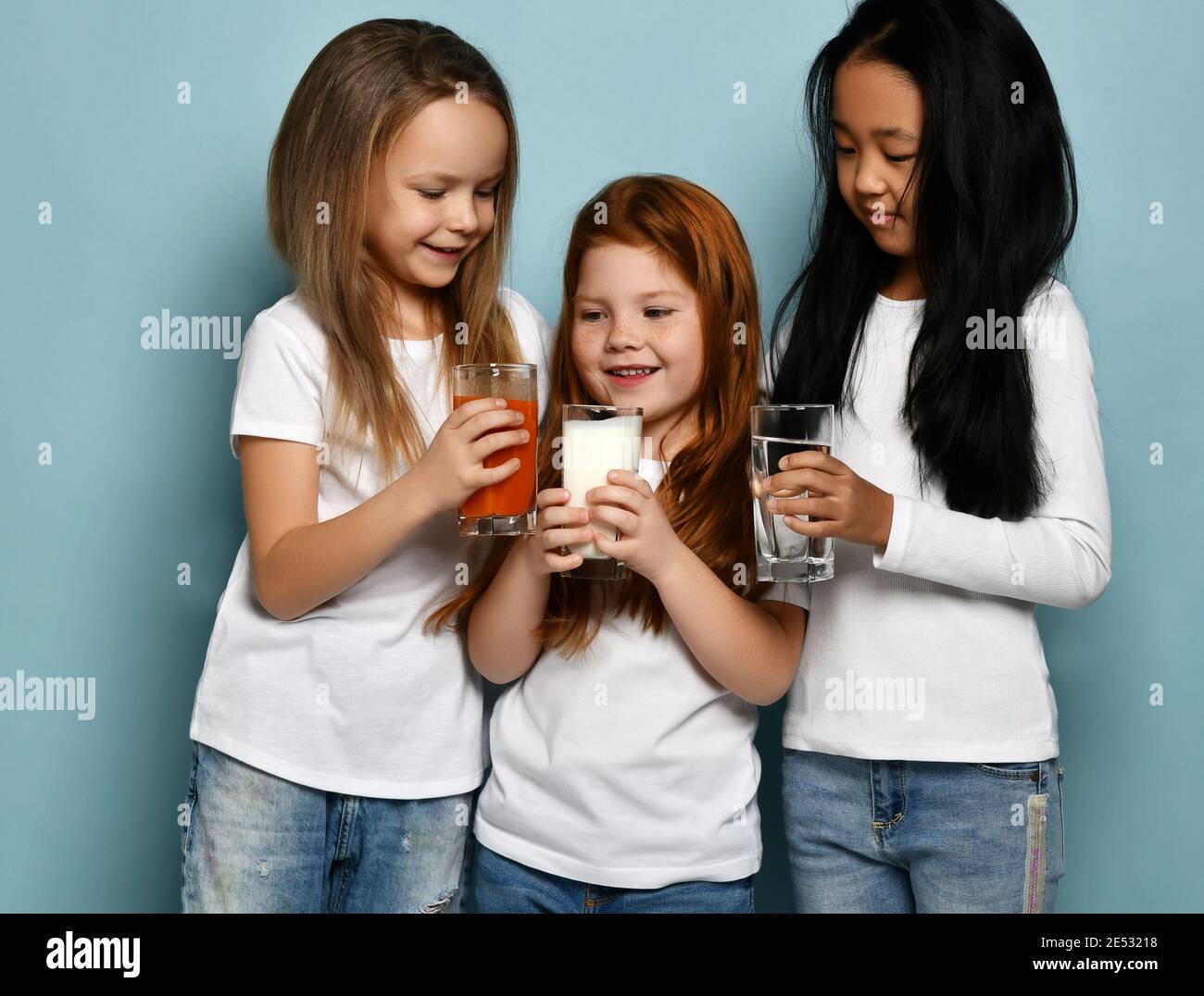 Nosotros mismos microondas Dirección Tres amigas de niños alegres en camisetas blancas comparten sus bebidas  favoritas agua, leche y zumo para celebrar Fotografía de stock - Alamy
