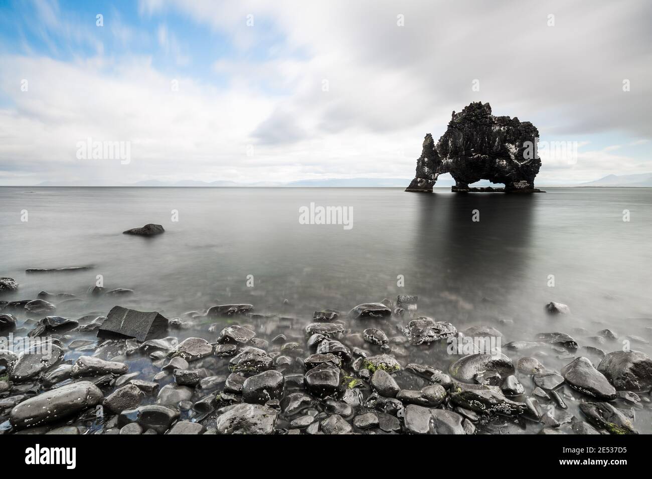 Paisaje islandés con guijarros en primer plano y la formación de roca negra conocida como Dragón sediento en el fondo, bajo un cielo nublado Foto de stock