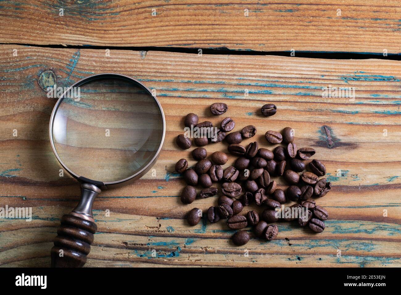 Granos de café y una lupa sobre una mesa de madera. Concepto de  investigación y búsqueda Fotografía de stock - Alamy