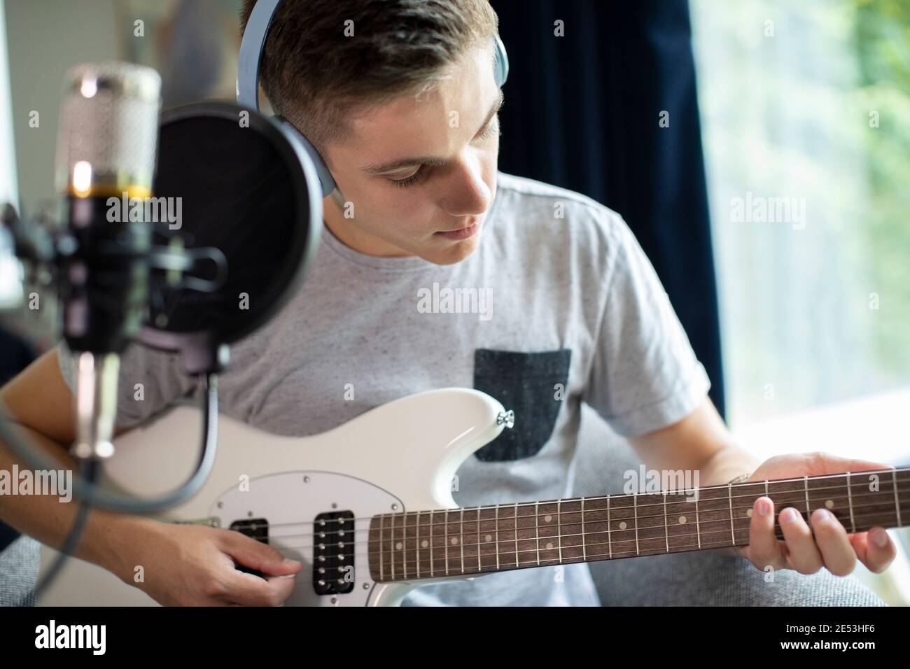 Adolescente tocando la guitarra y la grabación de música en casa Foto de stock