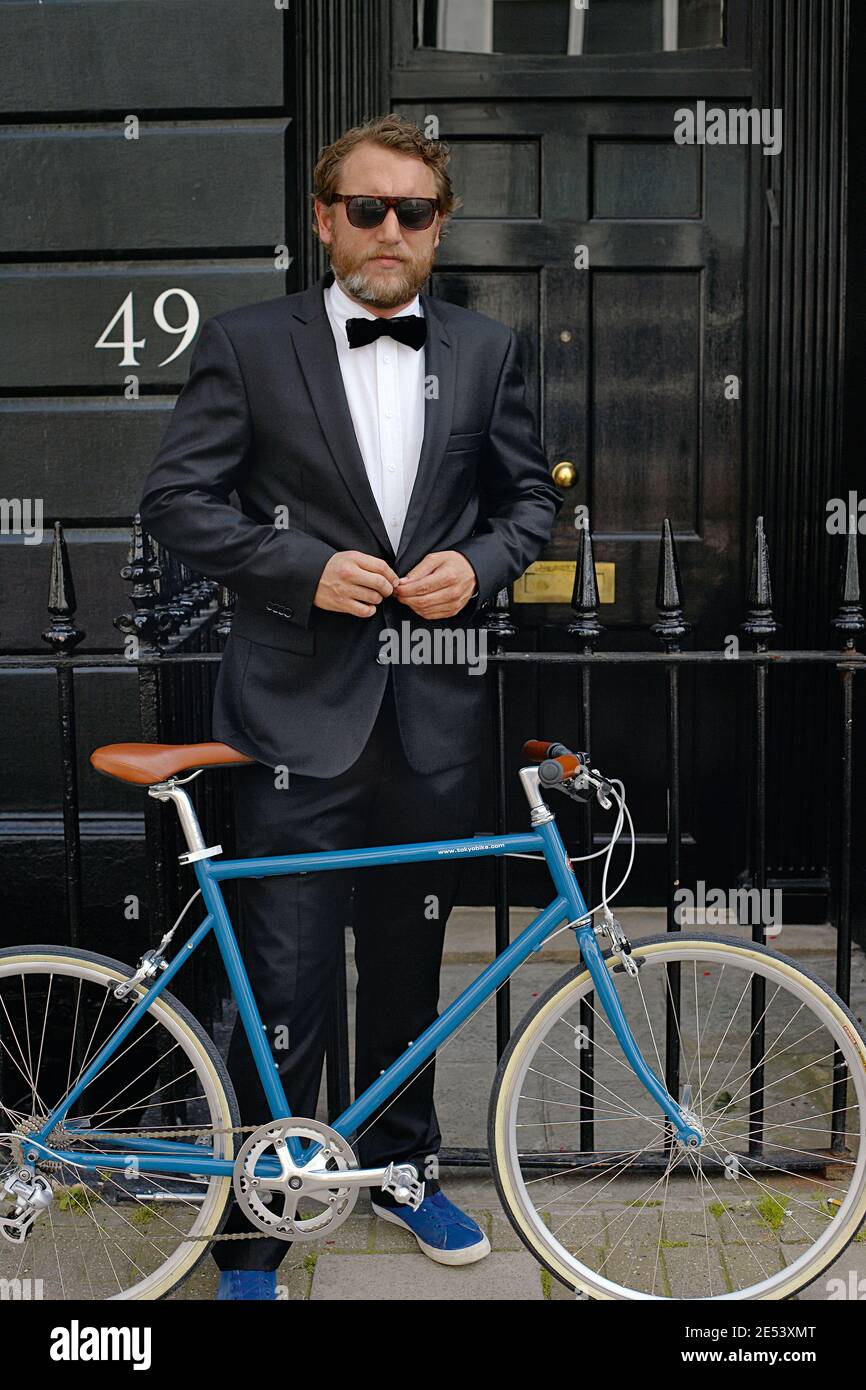 Hombre caucásico guapo parado al lado de la bicicleta con tuxedo con arco corbata Foto de stock