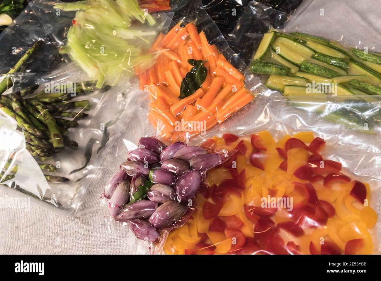 bolsas selladas al vacío para cocinar al vacío con pimientos y calabacines y chalotes, zanahorias frescas y espárragos Foto de stock