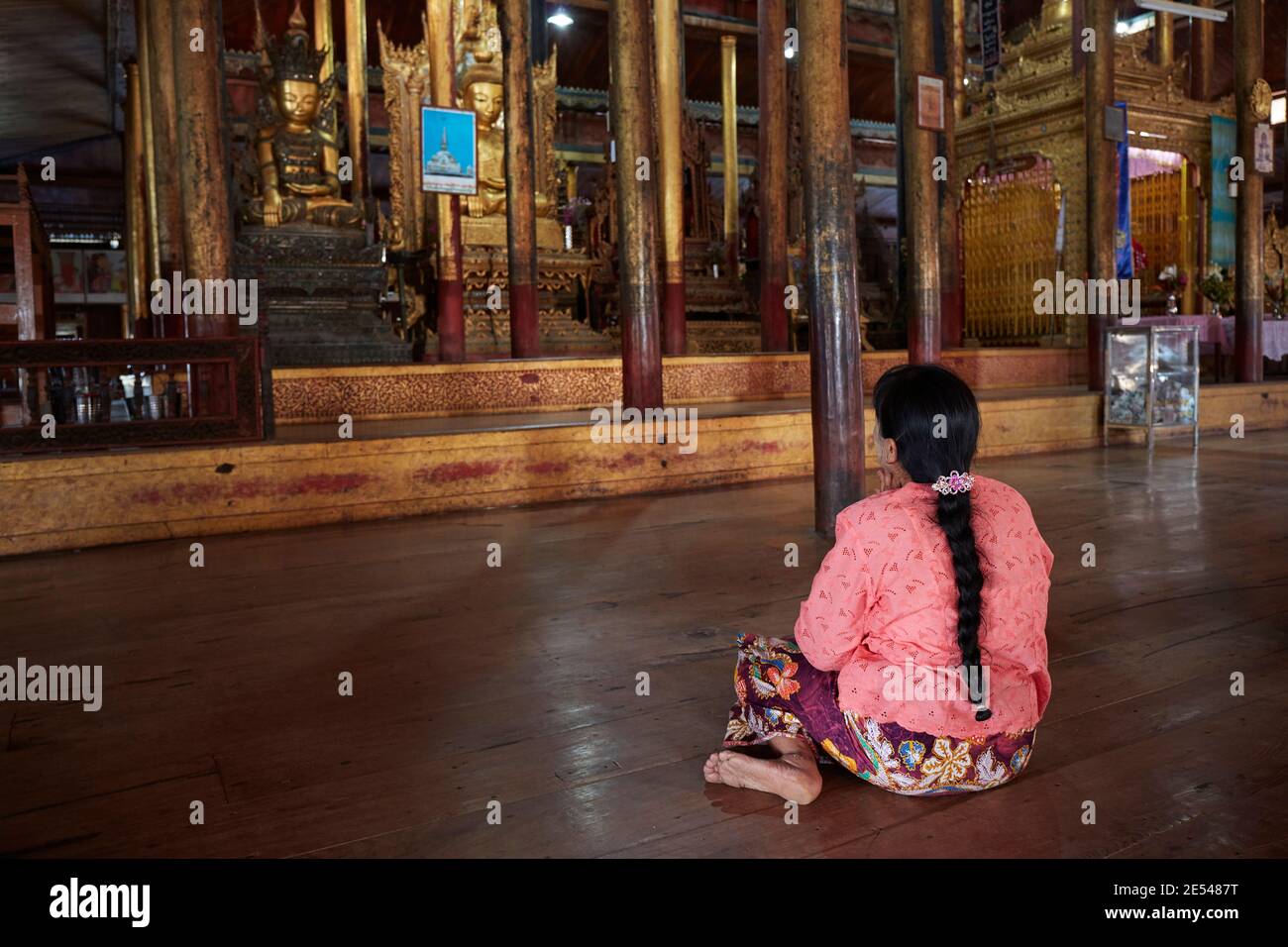 Una mujer ora dentro del monasterio de Nga Phe Kyaung, Lago Inle, Myanmar. Foto de stock