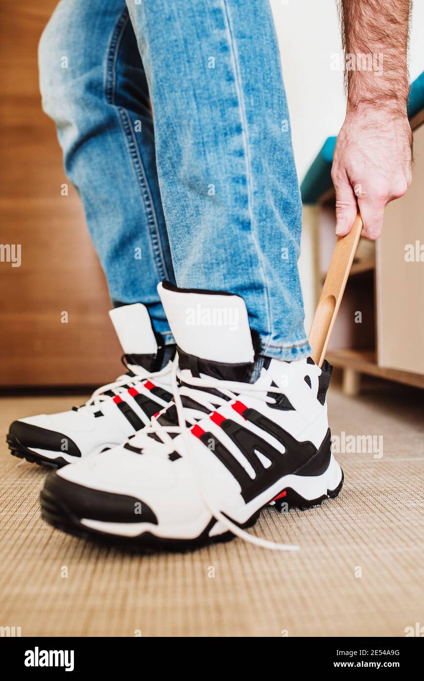 Un hombre se pone zapatos cómodos antes de salir de la casa - zapatillas  blancas con aislamiento de piel Fotografía de stock - Alamy