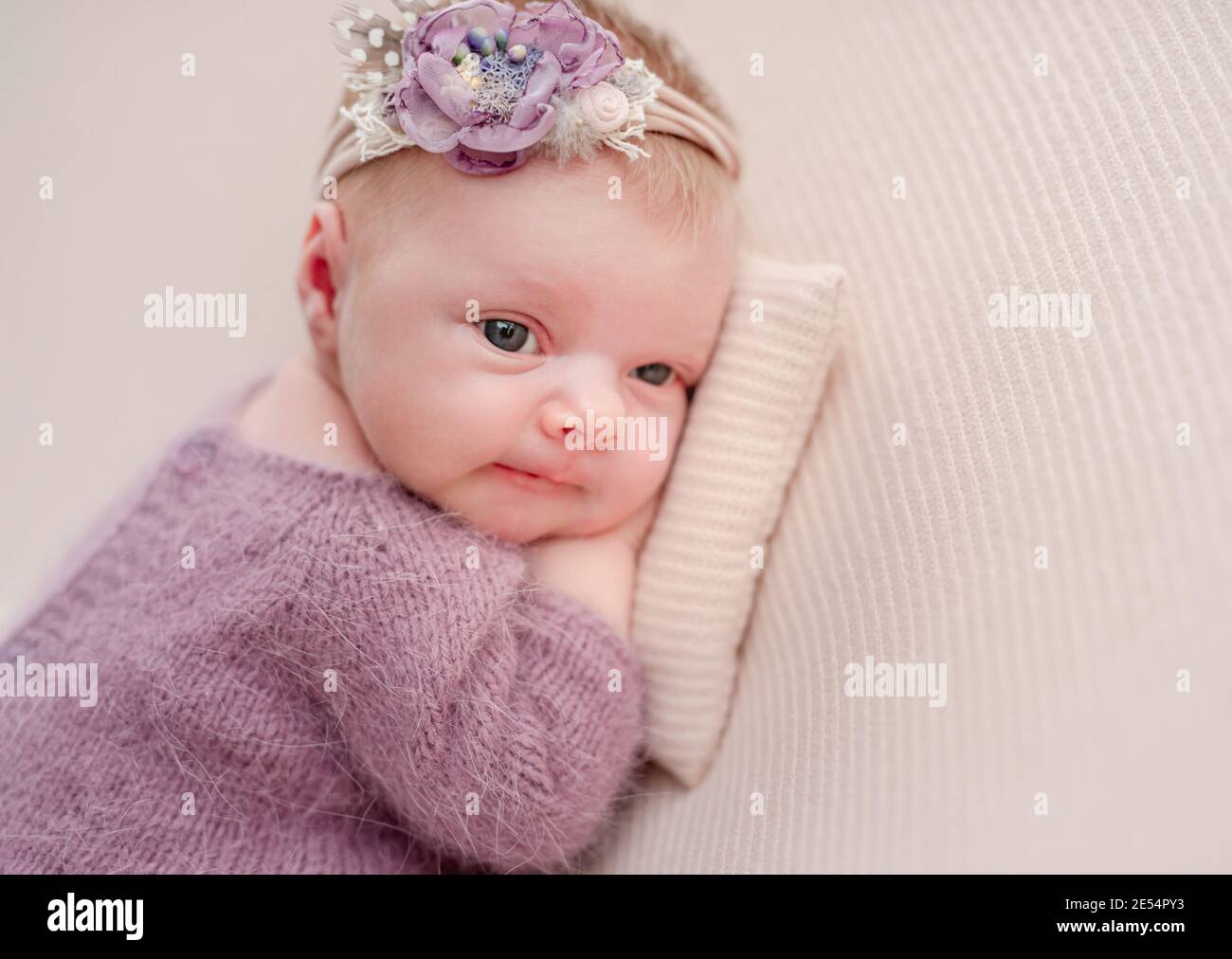 Despierta niña recién nacida con el diadem de la flor Foto de stock