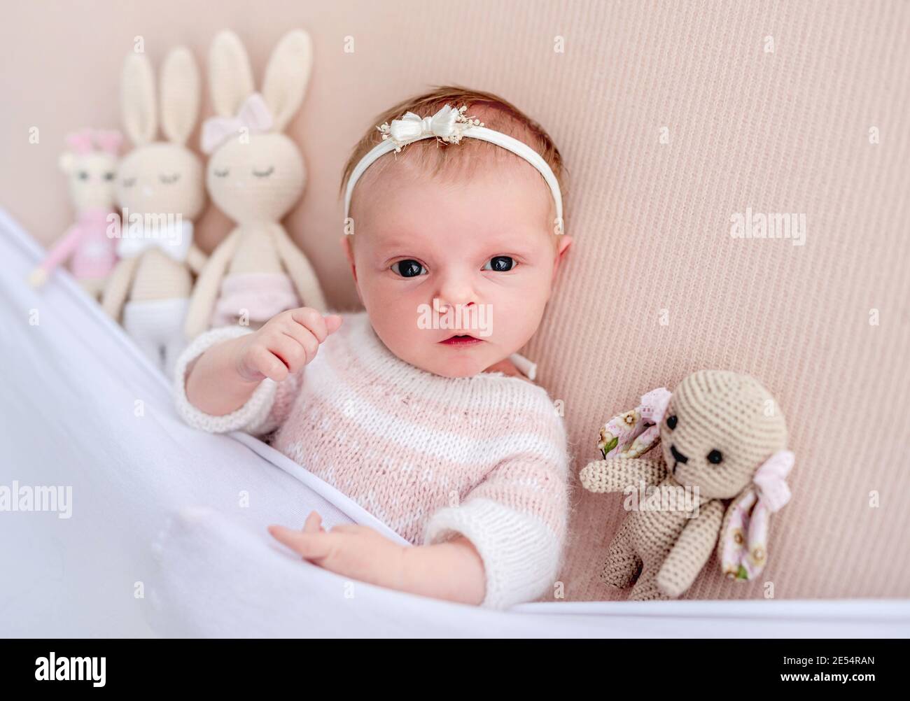 Niña recién nacida acostada junto a juguetes tejidos Foto de stock