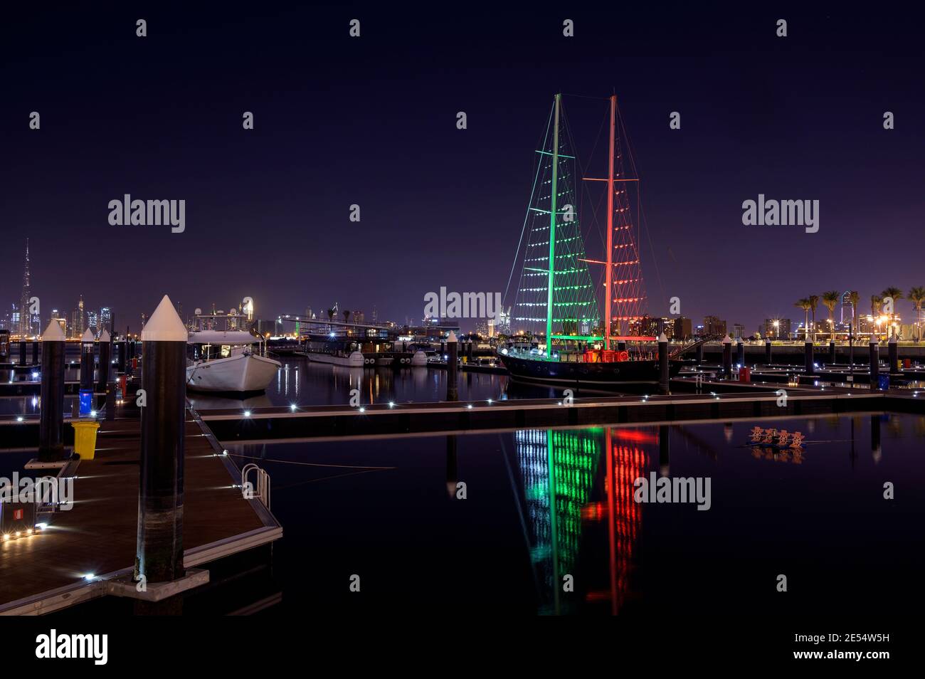 El horizonte del puerto de Dubai creek con barcos y barcos iluminados en colores de bandera para el día nacional de los emiratos árabes unidos capturados en el Ras al khor, Dubai Foto de stock
