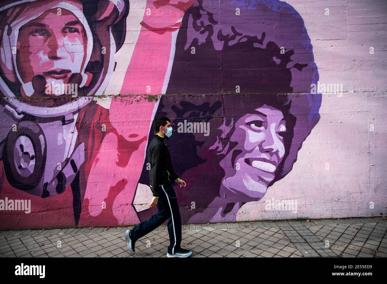 Madrid, España. 26 de enero de 2021. Un hombre que lleva una máscara para  protegerse contra la propagación del coronavirus (COVID-19) camina por un  mural feminista llamado "Unión hace fuerza" con los