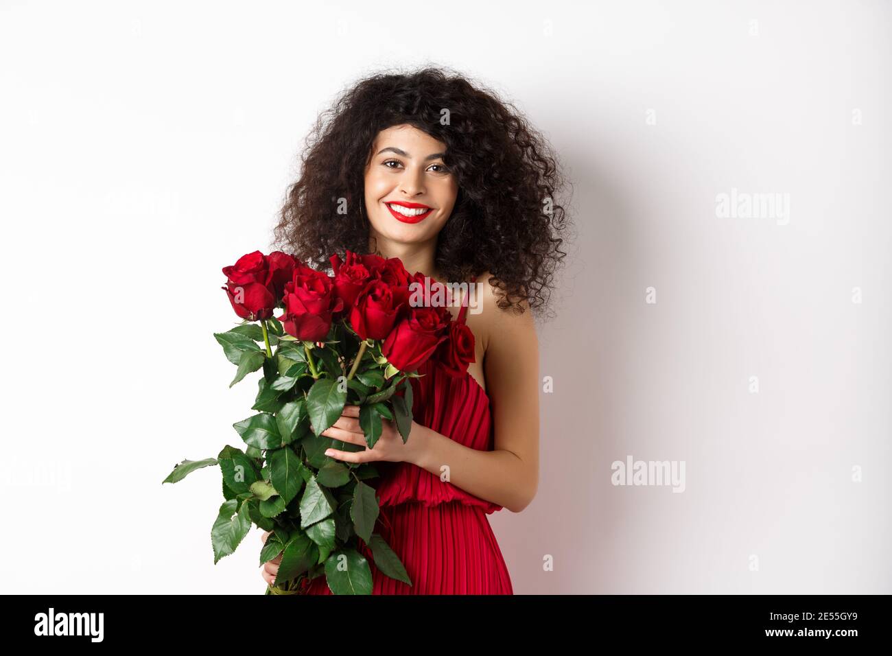 Hermosa mujer caucásica en rojo vestido de noche recibiendo ramo de flores. Chica con rosas rojas sonriendo en la cámara, teniendo una cita romántica en San Valentín Fotografía de stock - Alamy Hermosa mujer caucásica en rojo vestido de noche recibiendo ramo de flores. Chica con rosas rojas sonriendo en la cámara, teniendo una cita romántica en San Valentín Fotografía de stock - Alamy