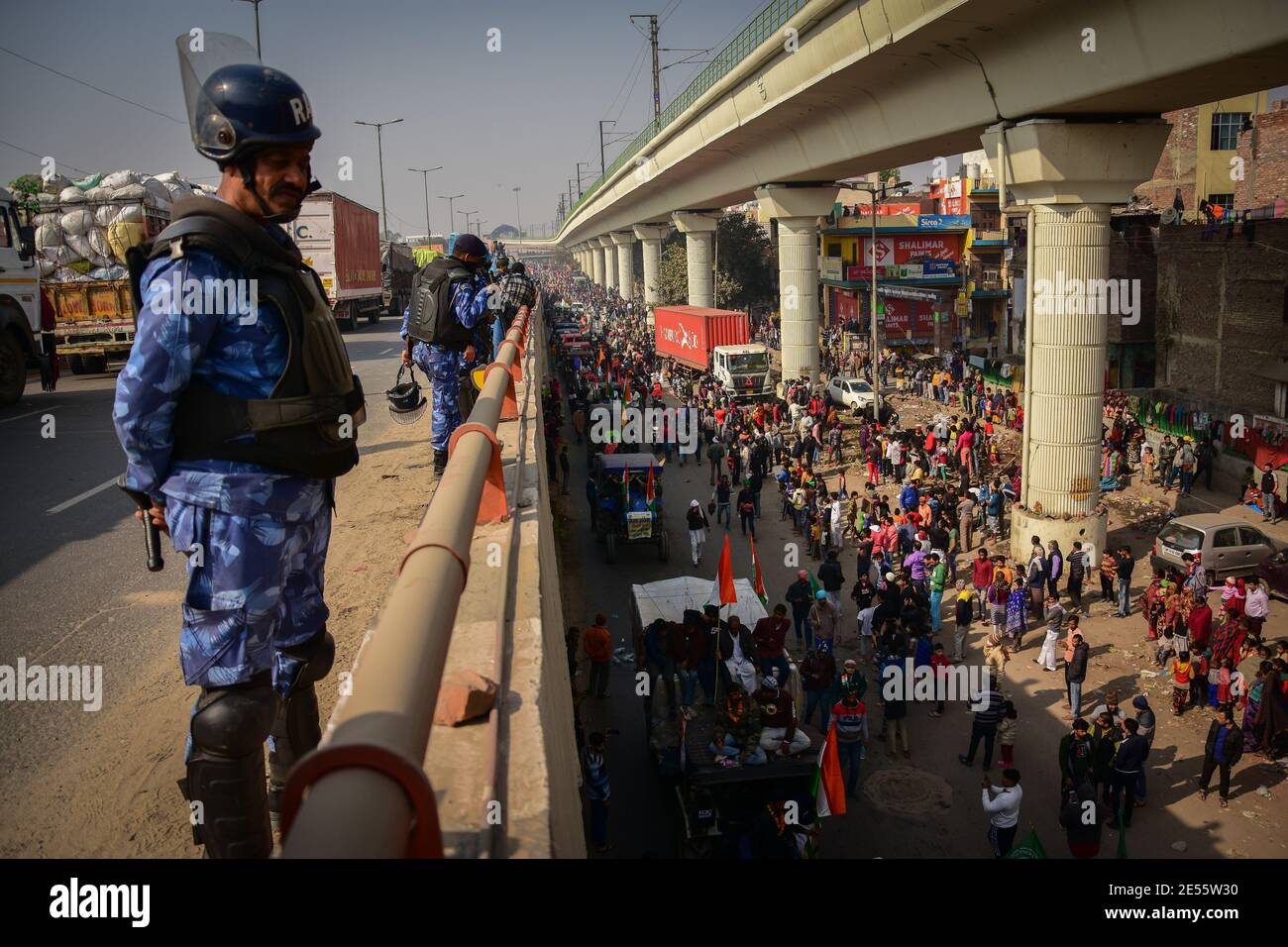 Un policía observa cómo los manifestantes participan en la manifestación.los agricultores que protestaban contra las reformas agrícolas violaron barricadas y se enfrentaron con la policía en la capital el día 72 de la República de la India. La policía disparó gases lacrimógenos para frenarlos, poco después de que un convoy de tractores atravesara las afueras de Delhi. (Foto de Manish Rajput / SOPA Images/Sipa USA) Foto de stock
