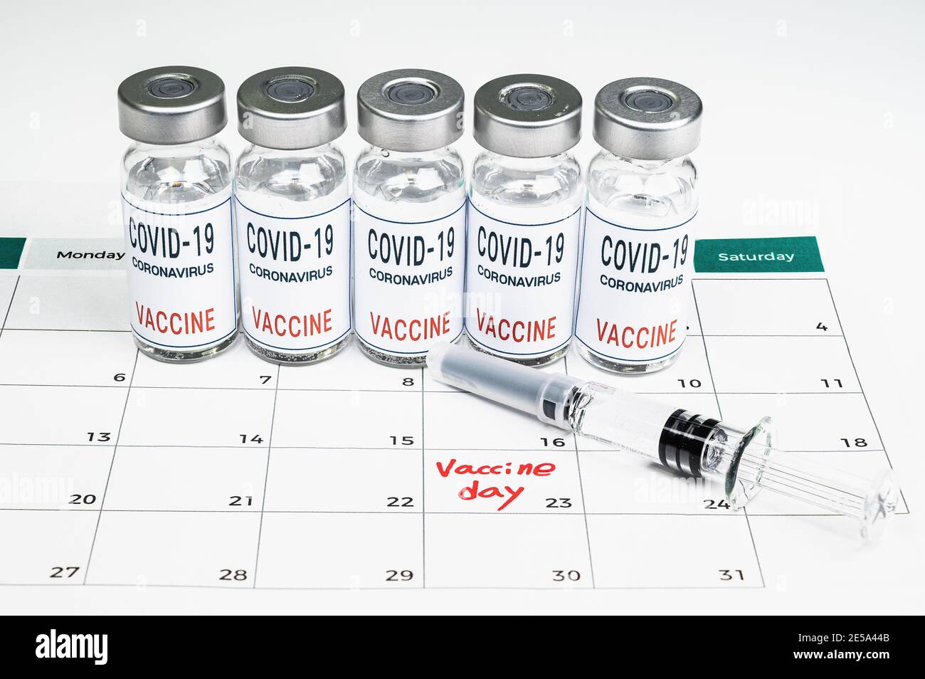 Un calendario con fechas de vacunación, una vacuna Covid-19, y un concepto médico con una jeringa. Foto de stock