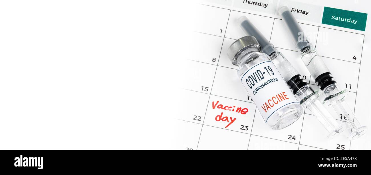 Un calendario con fechas de vacunación, una vacuna Covid-19, y un concepto médico con una jeringa. Foto de stock
