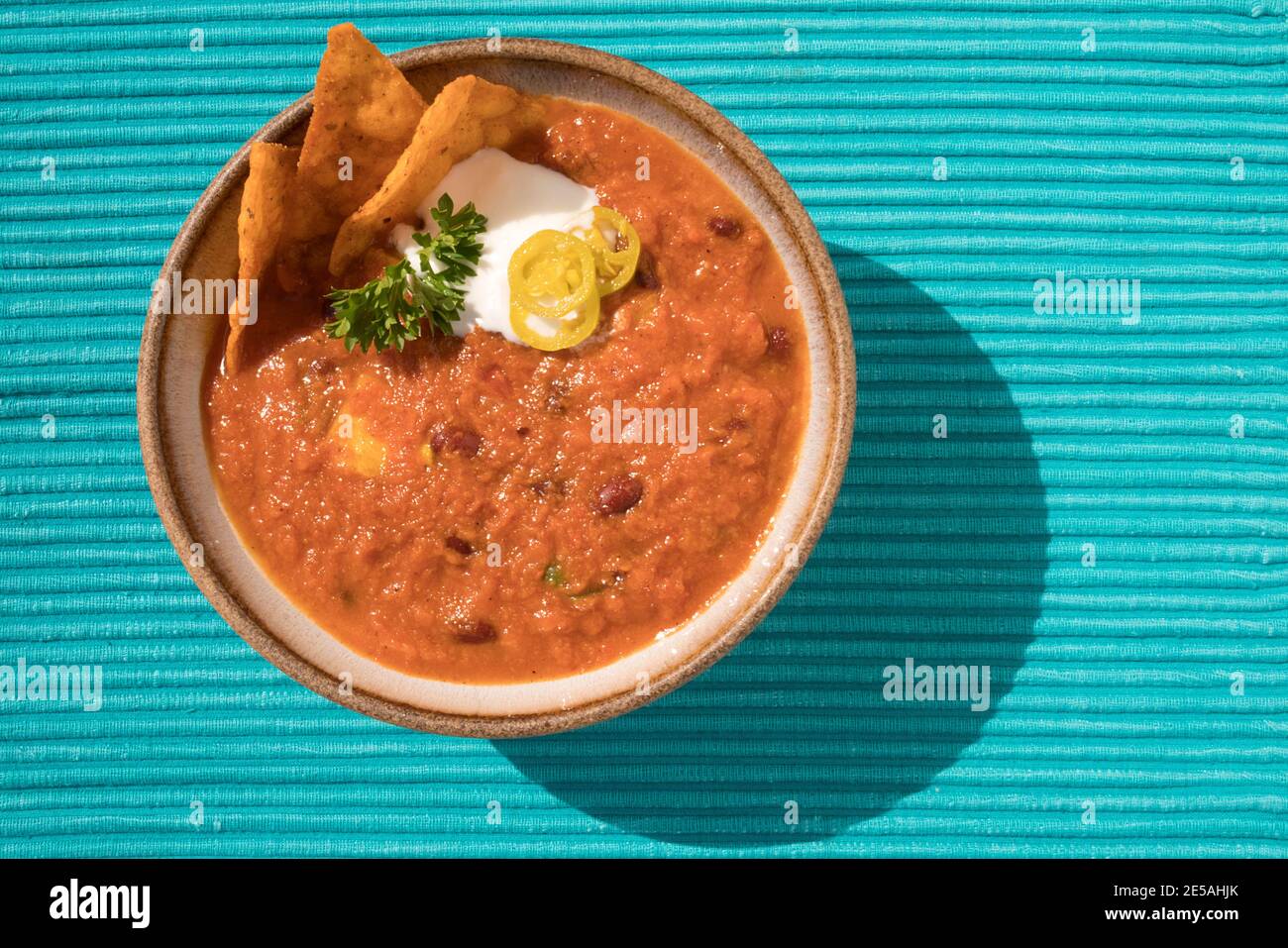 CHILE VEGETARIANO CASERO CON PATATAS FRITAS DE MAÍZ NACHO, CREMA AGRIA. PEREJIL Y PIMIENTA DE JALAPENO Foto de stock