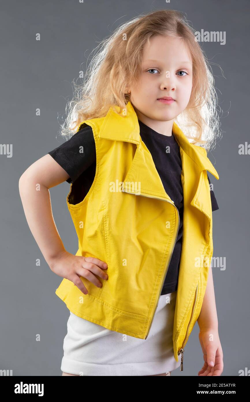 Hermosa niña rubia en una chaqueta amarilla sobre un fondo gris. Niña de cinco años. Modelos de pruebas para niño Fotografía de stock - Alamy
