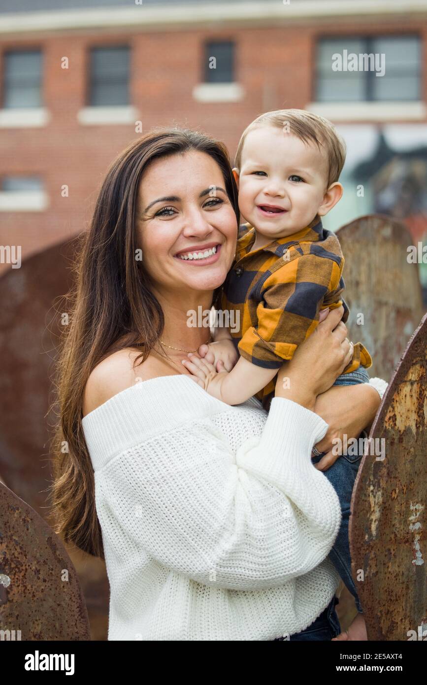 Una hermosa mamá con el largo marrón sosteniendo a su bebé chico Fotografía de stock - Alamy
