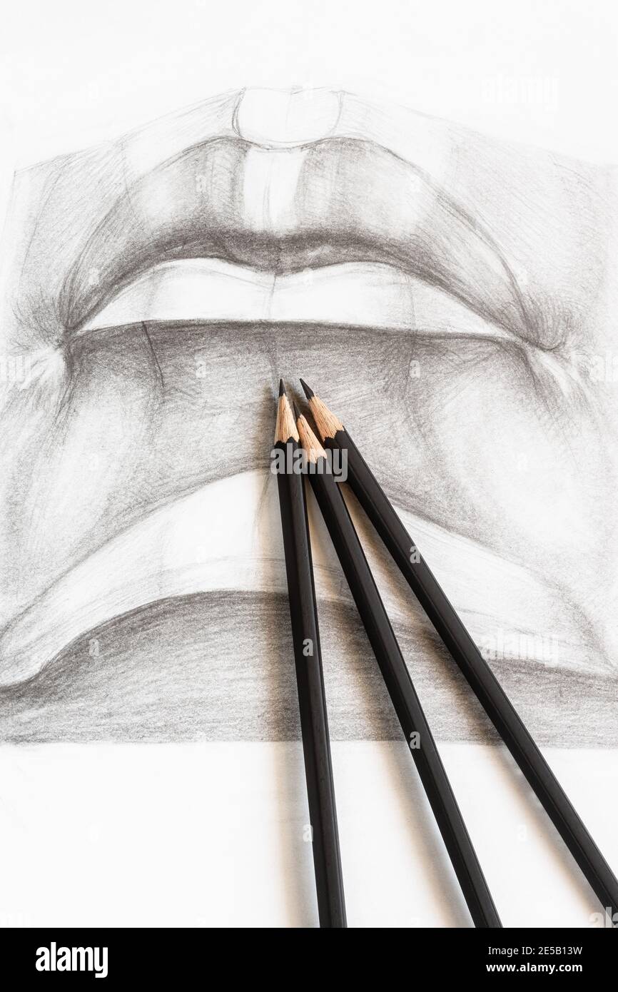lápices de grafito de madera en dibujo académico de labios masculinos de cerca Foto de stock
