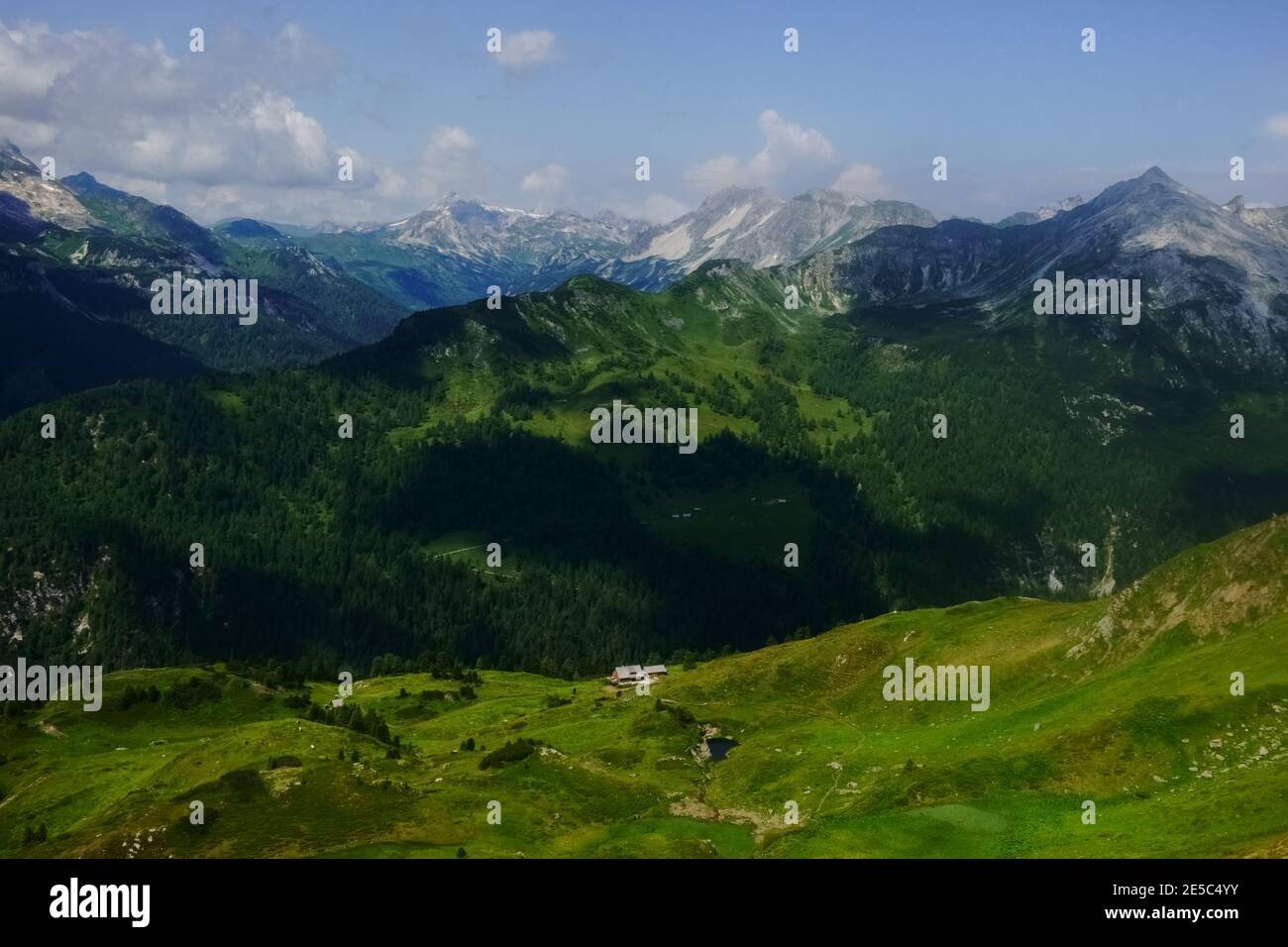 precioso paisaje de montaña con verdes colinas y una cabaña alpina mientras se hace senderismo Foto de stock