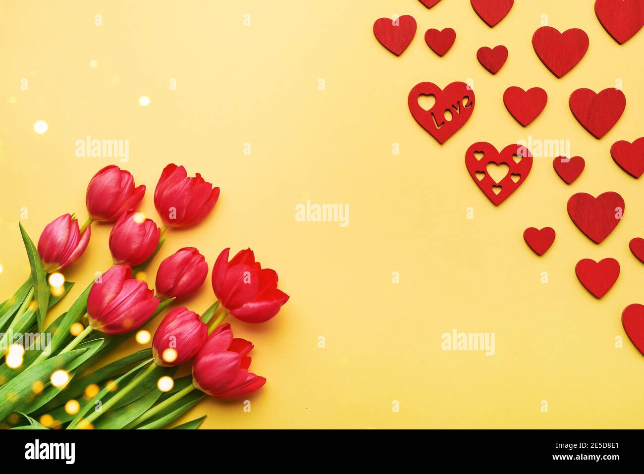 Tarjeta de felicitación para San Valentín. Ramo de tulipanes rojos y corazones rojos sobre fondo amarillo Foto de stock