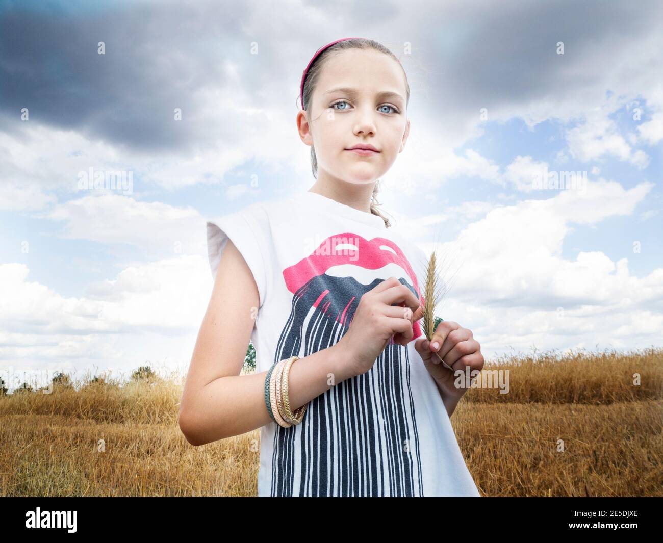 Hermosa chica de pie en un campo que sostiene una oreja de trigo, Polonia Foto de stock