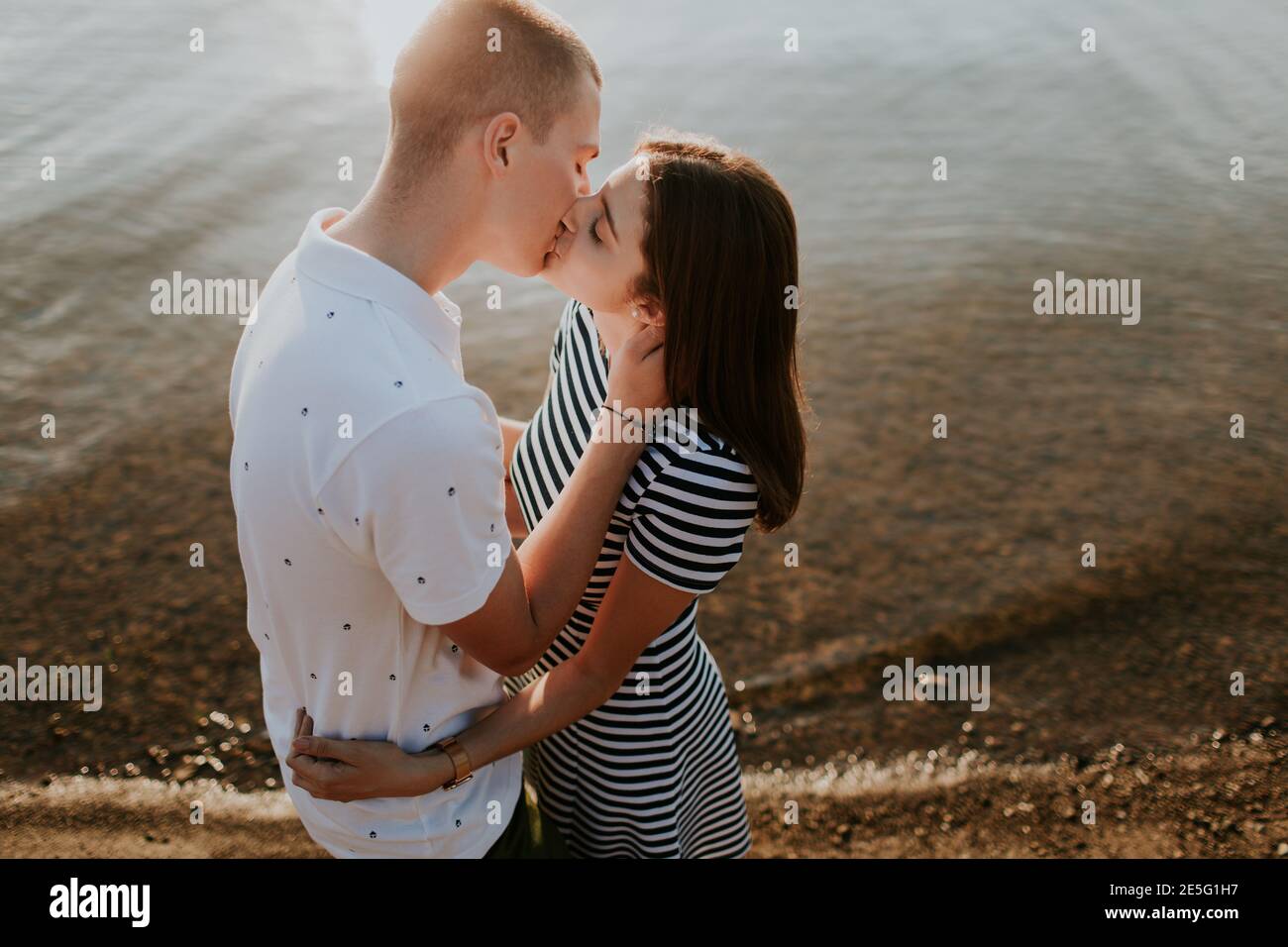 Cerca de una pareja enamorada besando en el mar al atardecer. Retrato de novio y novia abrazando y besando en la playa en la cálida noche de verano. Foto de stock