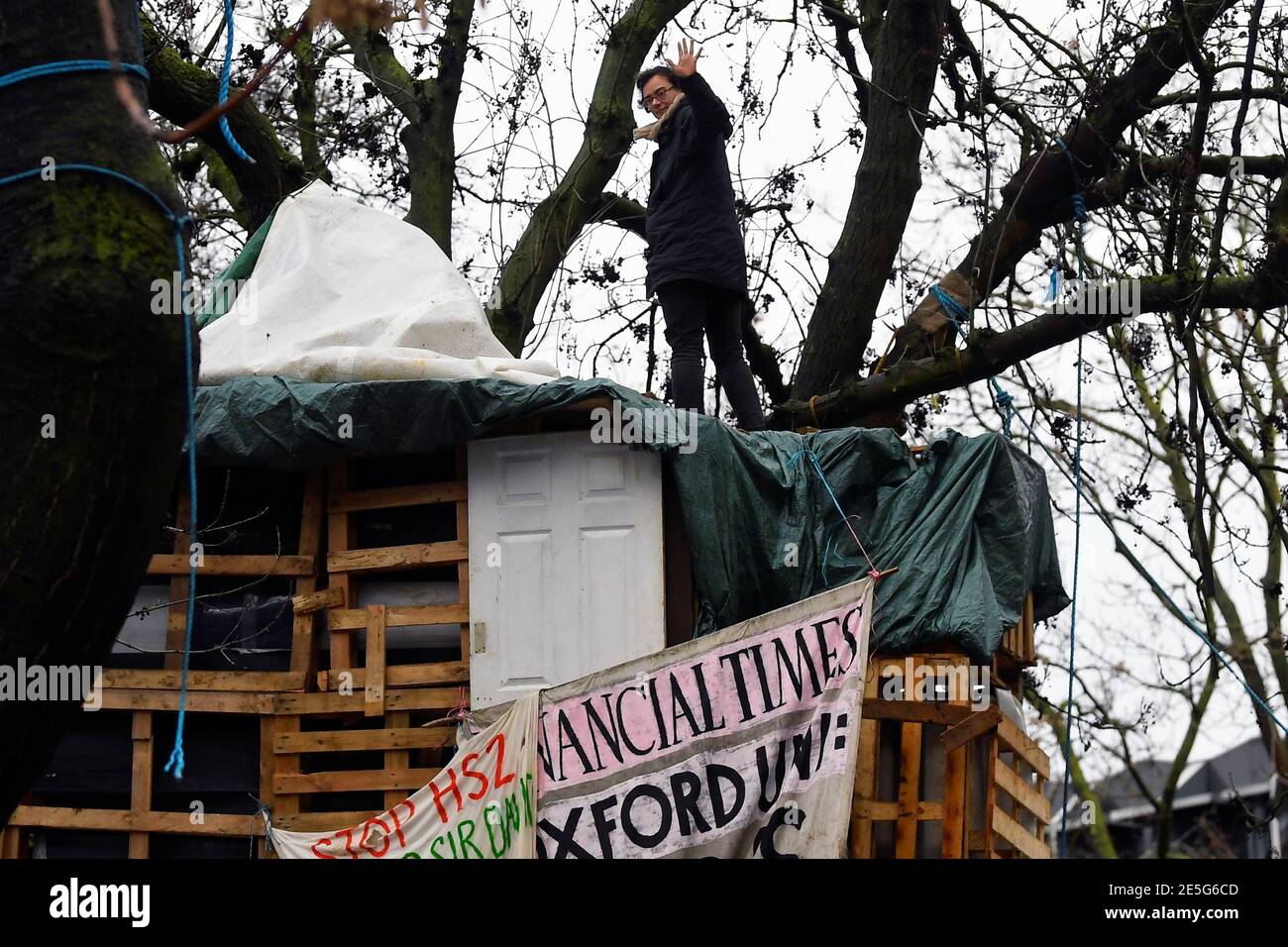 Un activista de la rebelión de extinción ondea sobre un árbol en un campamento improvisado, mientras otros manifestantes ocupan túneles bajo Euston Square Gardens para protestar contra el ferrocarril de alta velocidad HS2, en Londres, Gran Bretaña 28 de enero de 2021. REUTERS/Toby Melville Foto de stock