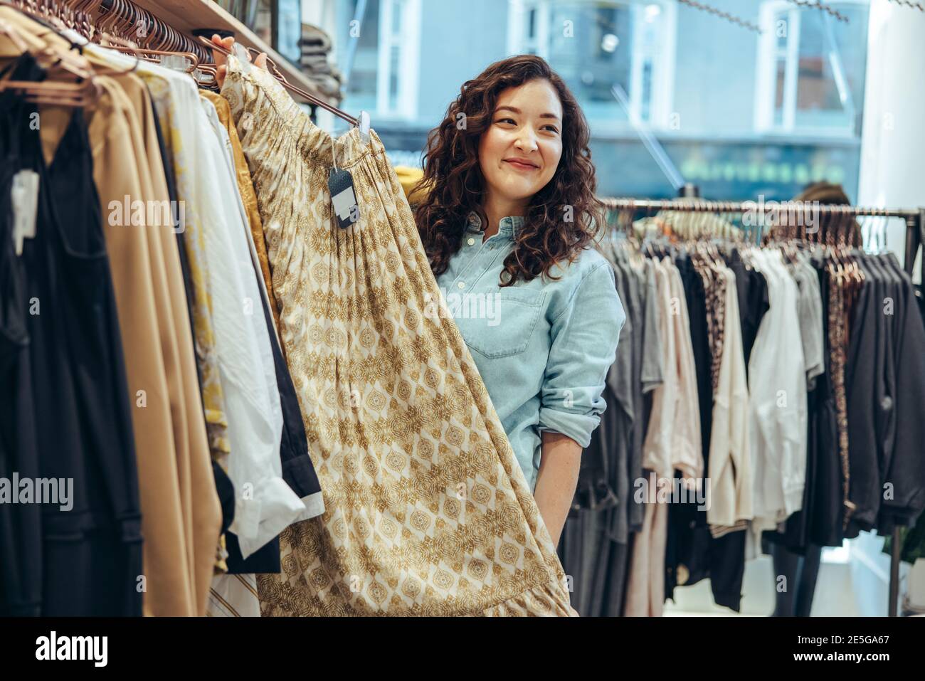 Mujer que trabaja en una tienda de ropa que ayuda al cliente. Vendedor  sosteniendo una falda colgando en el estante y mostrando al comprador  Fotografía de stock - Alamy