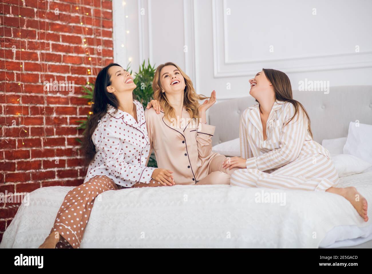 Tres bonitas chicas en pijama sentadas en una cama Fotografía de stock -  Alamy