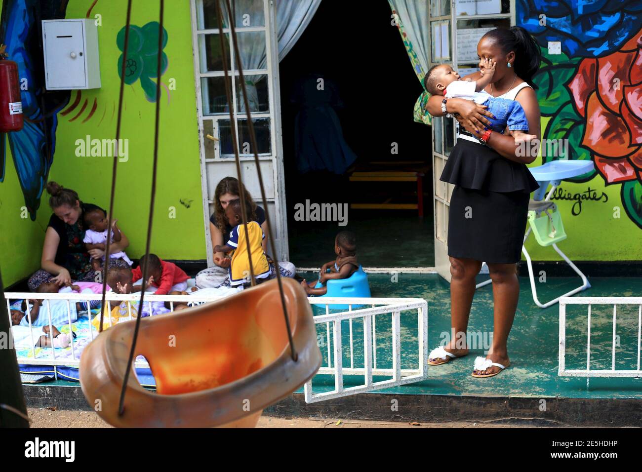 Voluntarios locales y extranjeros juegan con niños abandonados en una casa en la capital de Uganda, Kampala, 14 de mayo de 2015. Las familias ugandesas han sido sobornadas, engañadas o coaccionadas para entregar a sus hijos a ciudadanos estadounidenses y otros extranjeros para su adopción, según una investigación de la Fundación Thomson Reuters. Foto tomada el 14 de mayo de 2015. REUTERS/James Akena Foto de stock