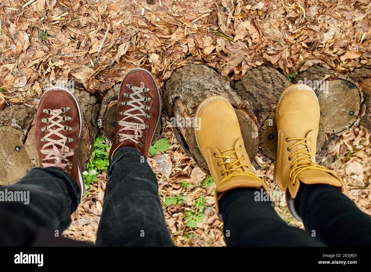 Botas de senderismo para parejas jóvenes modernas en el tocón de madera  sobre hojas caídas de otoño en el bosque, concepto de viaje al aire libre,  vista superior, Amor para siempre, día