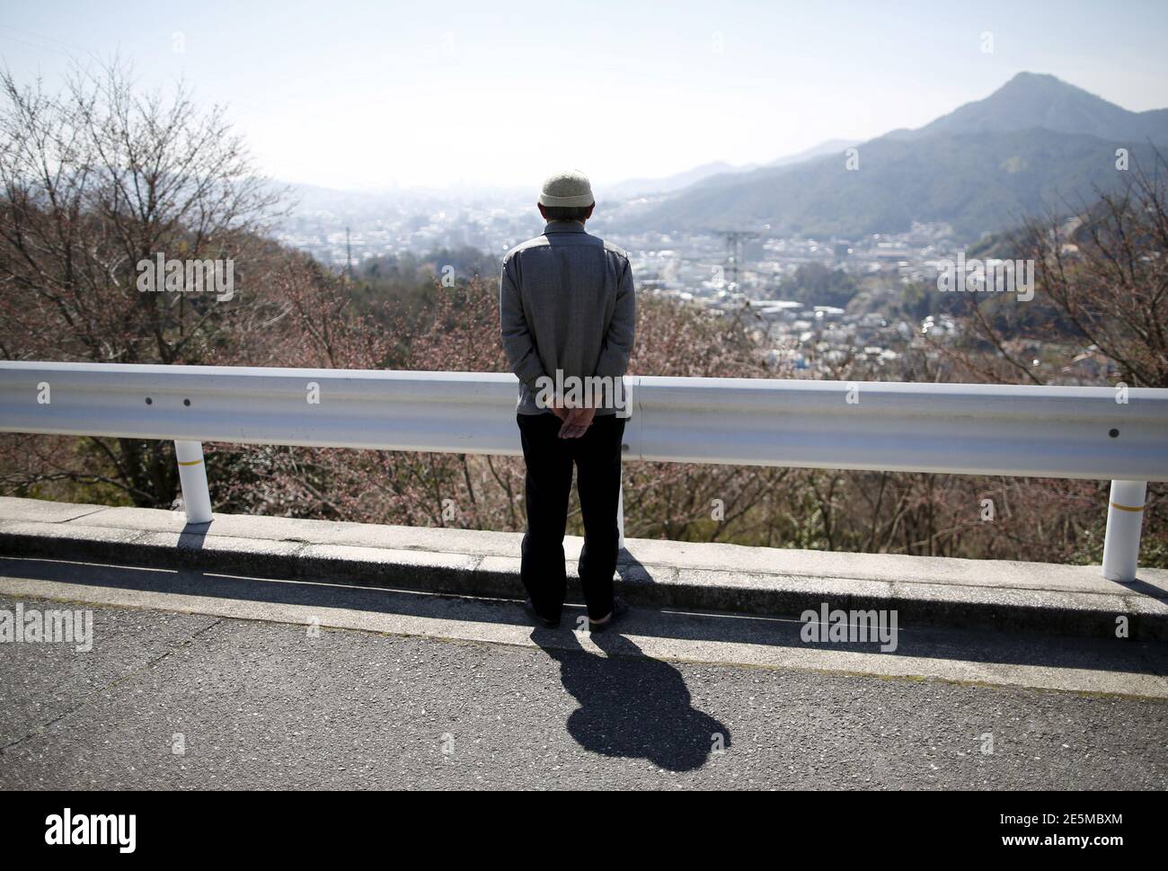 Fumiaki Kajiya, un sobreviviente de una bomba atómica de 76 años y profesor de escuela jubilado, mira hacia el centro de la ciudad desde la calle frente a su casa en Hiroshima, Japón occidental, el 27 de marzo de 2015. A medida que se acerca el 70º aniversario del primer ataque nuclear del mundo, muchos sobrevivientes todavía encuentran demasiado doloroso para hablar. Pero con sus filas menguando, otros están decididos a transmitir sus experiencias a las generaciones más jóvenes. Un bombardero estadounidense lanzó la bomba atómica sobre Hiroshima el 6 de agosto de 1945, matando a unos 140,000 a finales de año, de los 350,000 que vivían en la ciudad. La ciudad todavía tiene som Foto de stock