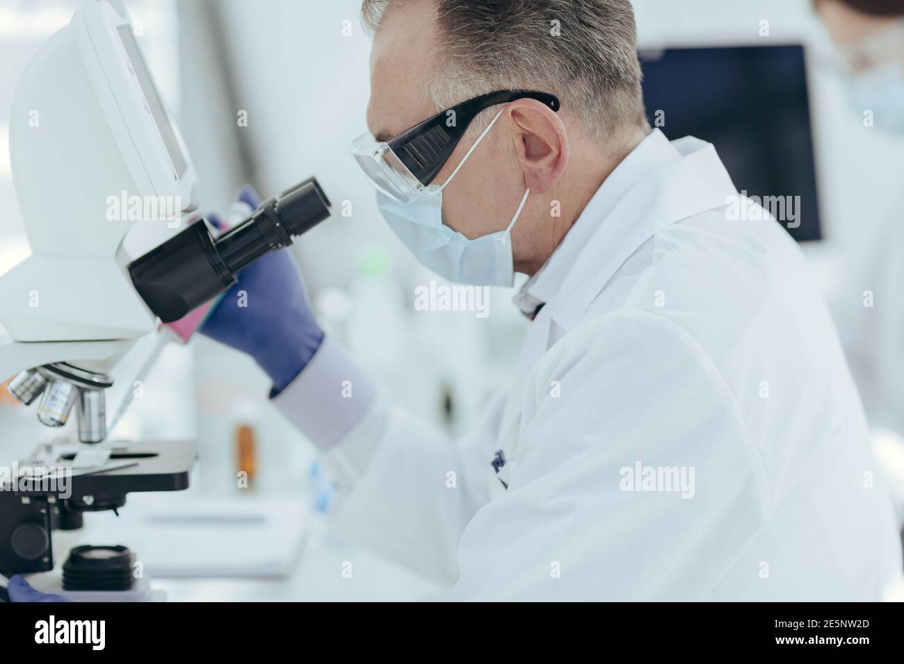 microbiólogo un científico mirando a través de un microscopio. Foto de stock