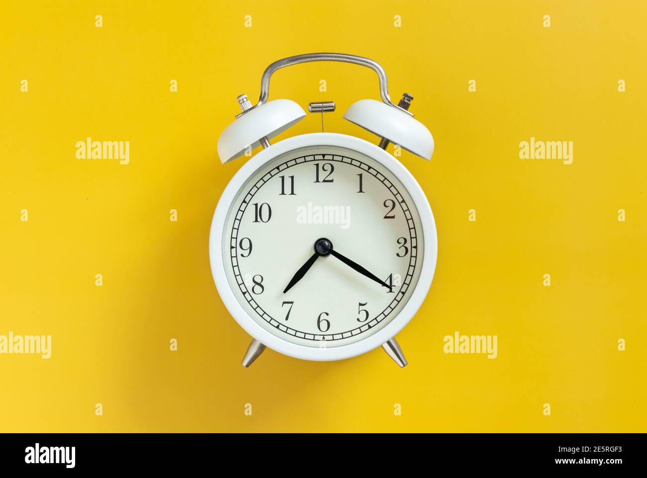 blanco círculo retro clásico reloj despertador analógico con aguja de reloj aislado sobre fondo amarillo vacío con espacio de copia. Foto de stock