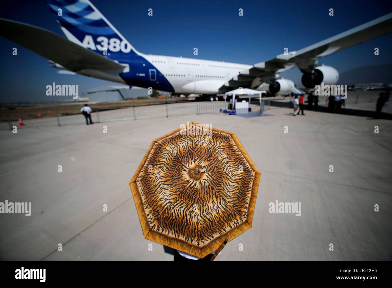 Una mujer que usa un paraguas pasa por un Airbus A380 durante la Feria  Internacional del Aire y el espacio (FIDAE) en el aeropuerto internacional  de Santiago, 25 de marzo de 2014.