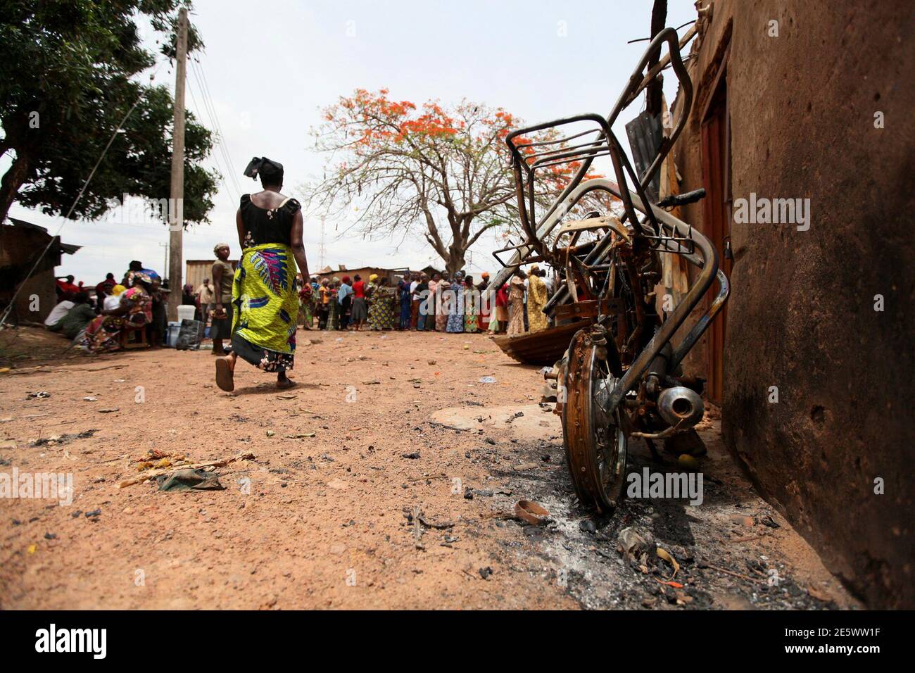 A woman walks past a burnt motocycle to vote at a polling unit in Kachia village, where violence erupted last week, in Nigeria's northern state of Kaduna April 28, 2011. Voters trickled out to polling stations on Thursday in two states in northern Nigeria where rioting killed hundreds last week, under the watchful eye of policemen on horseback and soldiers manning barricades. REUTERS/Afolabi Sotunde (NIGERIA - Tags: POLITICS ELECTIONS CIVIL UNREST) Foto de stock