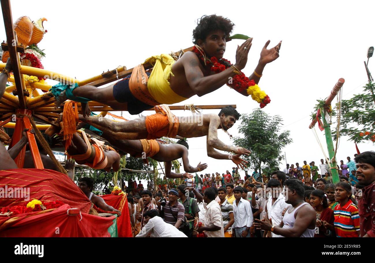 Hindu devotees hang from wooden poles using hooks pierced through their