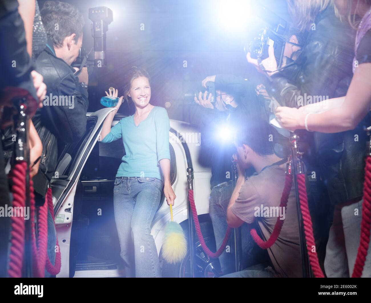 Mujer emocionada con equipo de limpieza saliendo de la limusina frente de paparazzi Foto de stock