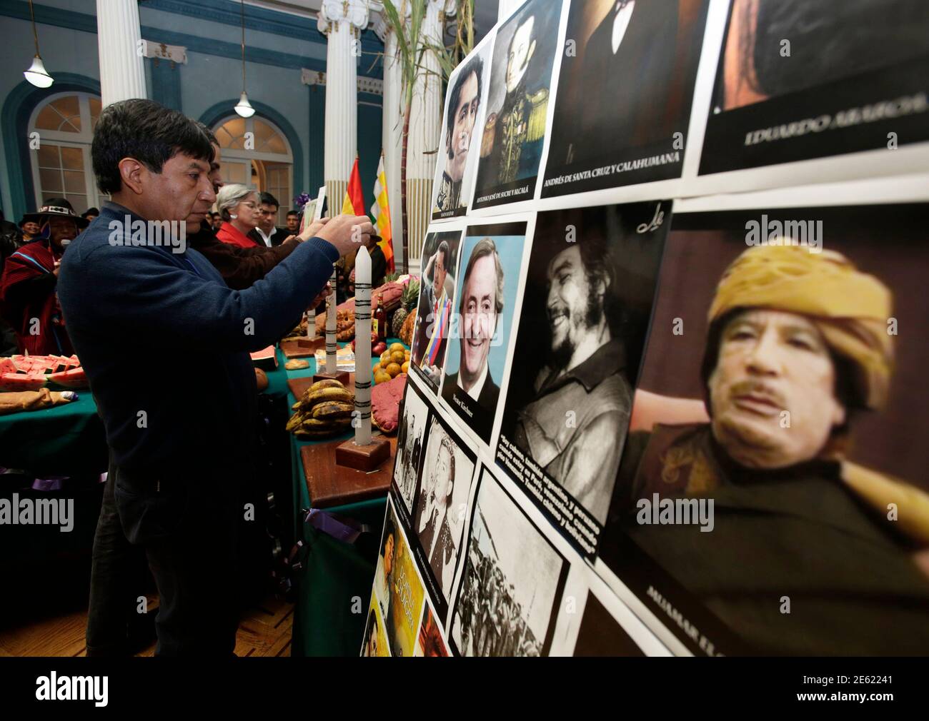 Bolivian Foreign Minister David Choquehuanca (L) lights a candle during an All Saints' Day celebration in front of Images of Libya's Muammar Gaddafi, Argentine Ernesto "Che" Guevara, Nestor Kirchner and Venezuela's Hugo Chavez in La Paz, November 1, 2013. Traditionally, indigenous Bolivians celebrate All Saints Day by paying homage to their dead ones with a feast of home-baked, doll-shaped breads, fresh fruit and coca leaves and flowers. The syncretism practiced by the Aymaras, a blend of Catholicism and indigenous beliefs, calls for the offerings to be neatly placed on top of graves, and then Foto de stock
