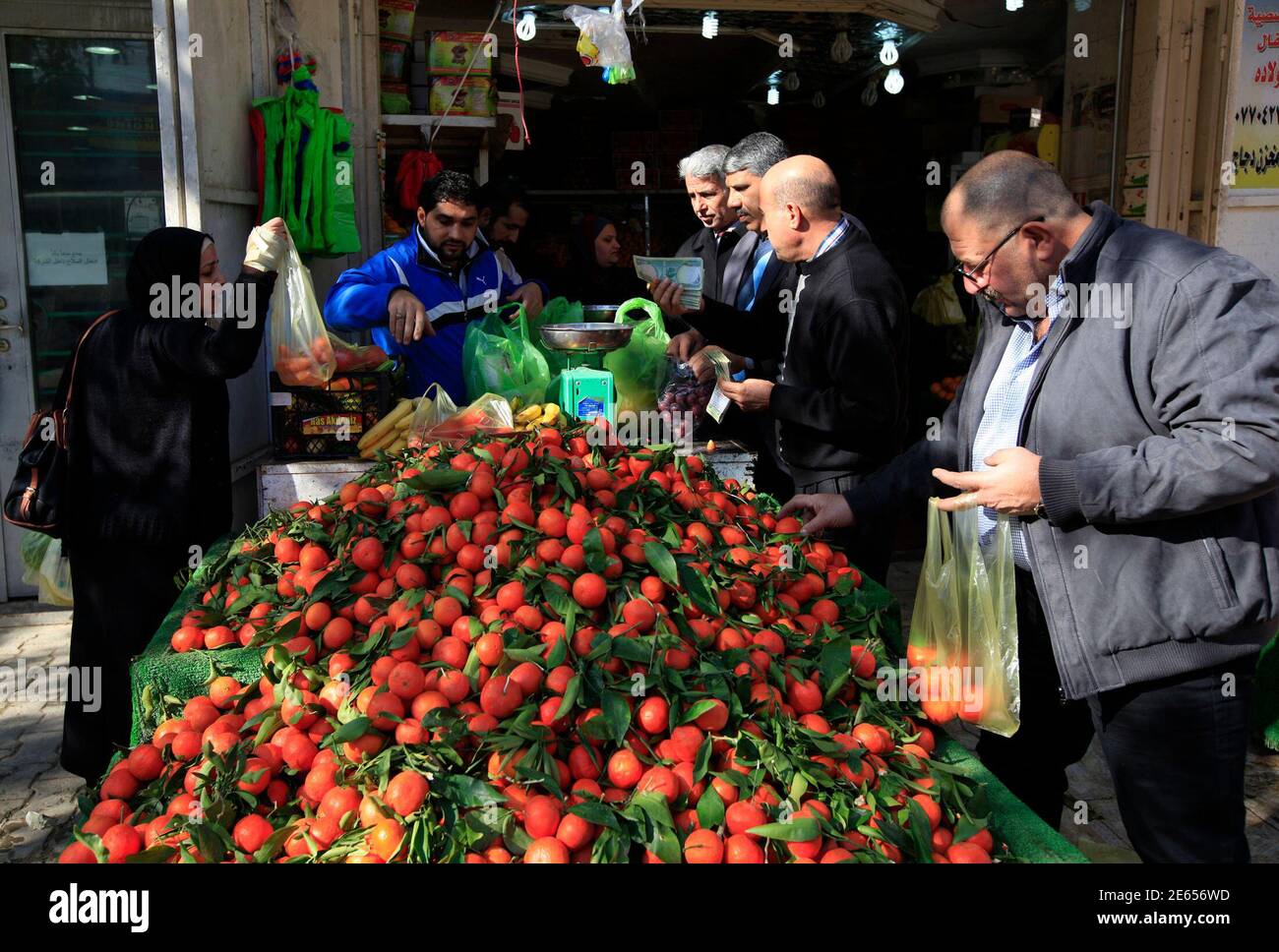 La gente compra comestibles en una tienda en Bagdad el 16 de enero de 2014. Al día siguiente de uno de los días más sangrientos de Irak durante meses, los compradores y conductores llenaron las calles de Bagdad el jueves, conscientes de que la muerte puede golpear en cualquier lugar, en cualquier momento. Al menos ocho bombas golpearon la capital, la mayoría en los distritos chiítas, el miércoles, matando a 40 personas e hiriendo a 88, mientras que los ataques en otros lugares llevaron el número de muertos a 78. REUTERS/Ahmed Saad (IRAK - Tags: SOCIEDAD CIVIL MALESTAR) Foto de stock