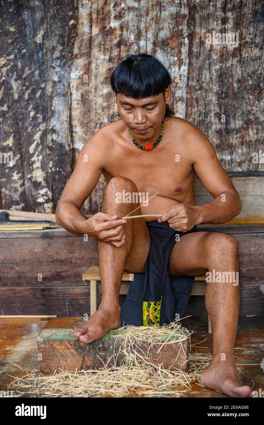 Orang Ulu hombre haciendo dardos de golpe para la pistola de aire Foto de stock