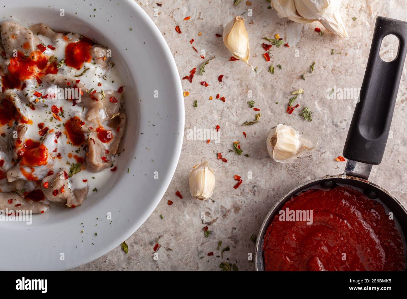 el manti turco tradicional es una forma de dumpling hecha con carne molida y servida en yogur de ajo y salsa de tomate sazonado con pimientos rojos machacados a Foto de stock