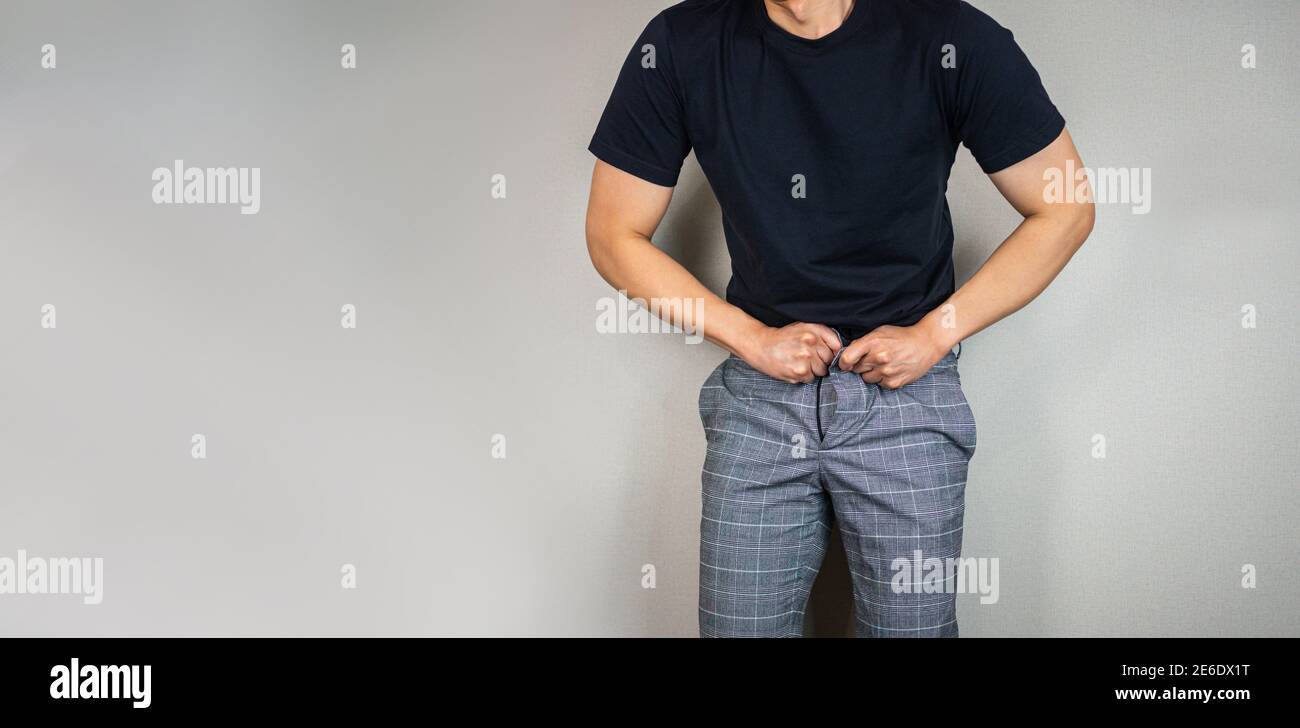 Usando pantalones apretados, el hombre tratando de enganchar los pantalones como aumento de peso Foto de stock